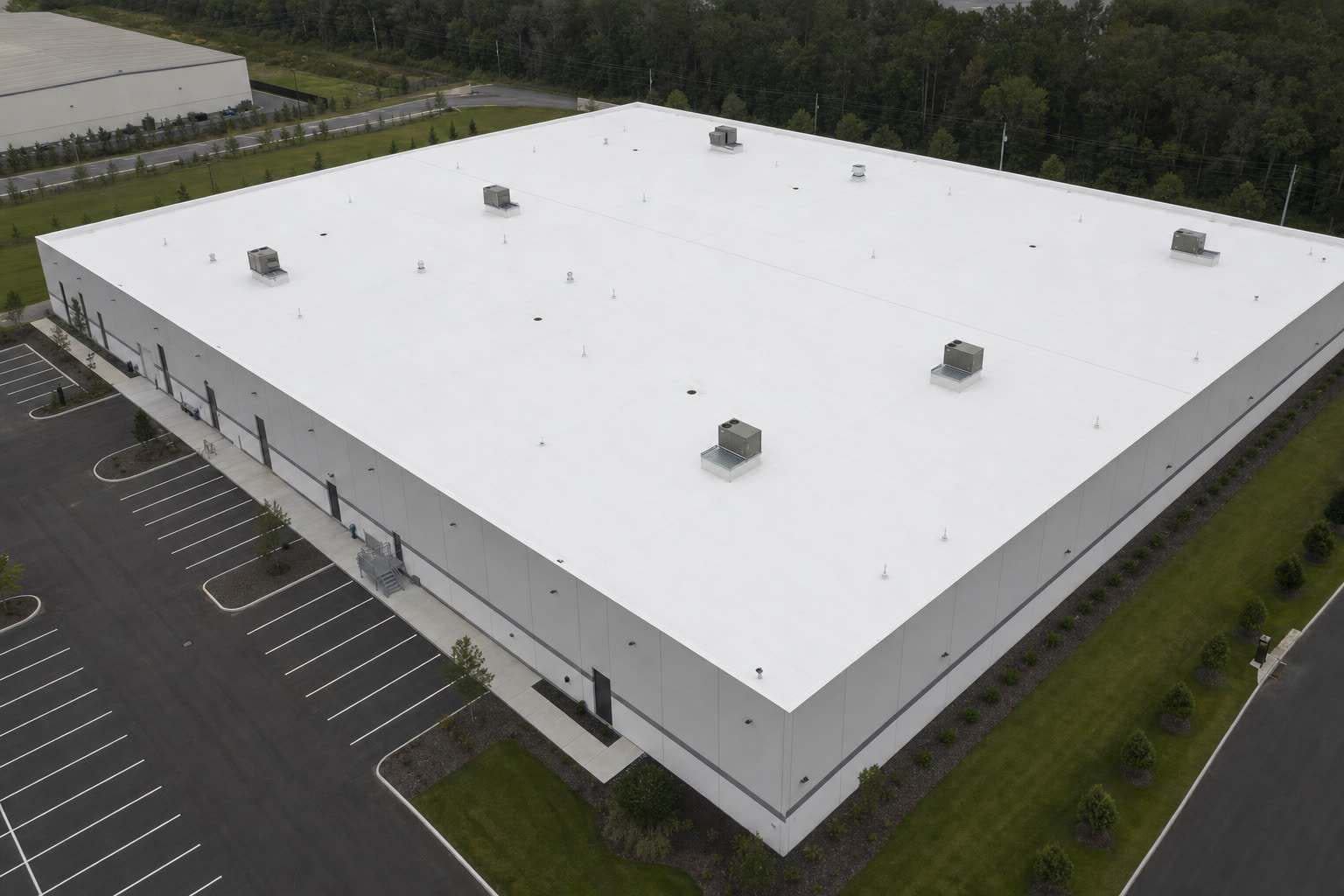 Aerial view of a white TPO membrane warehouse roof with rooftop HVAC units